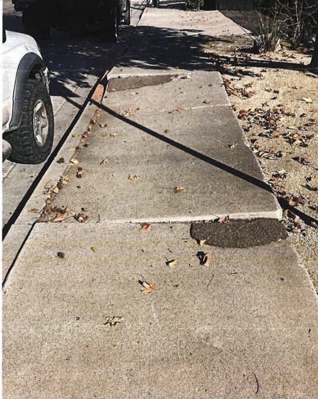 Damaged San Diego sidewalk before replacement — lifted, cracked panels with temporary asphalt patches