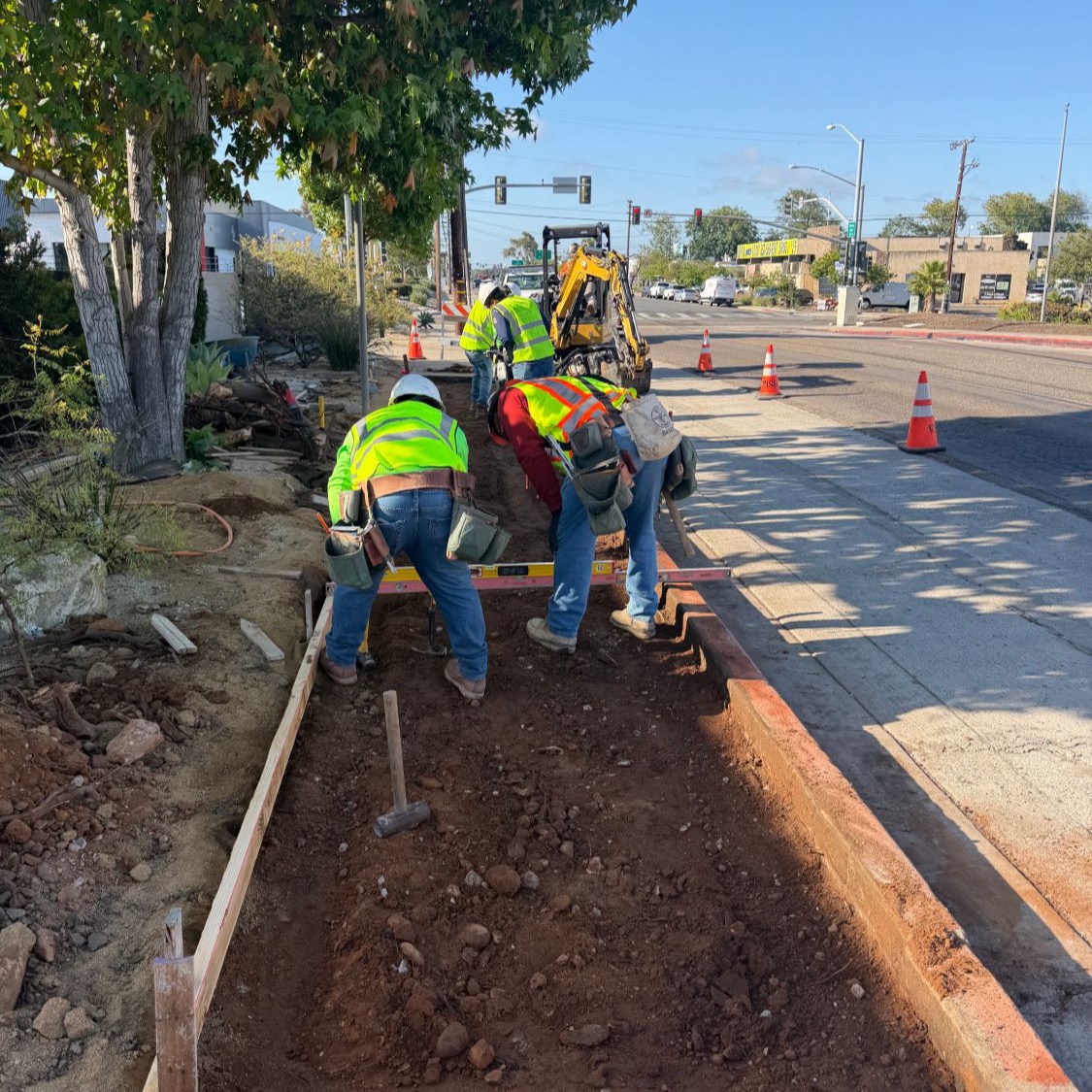 Crew setting wood forms and grading the base for a City sidewalk pour