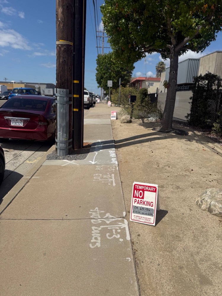 A San Diego sidewalk panel marked with the City's white paint for repair, with a temporary no-parking permit sign posted