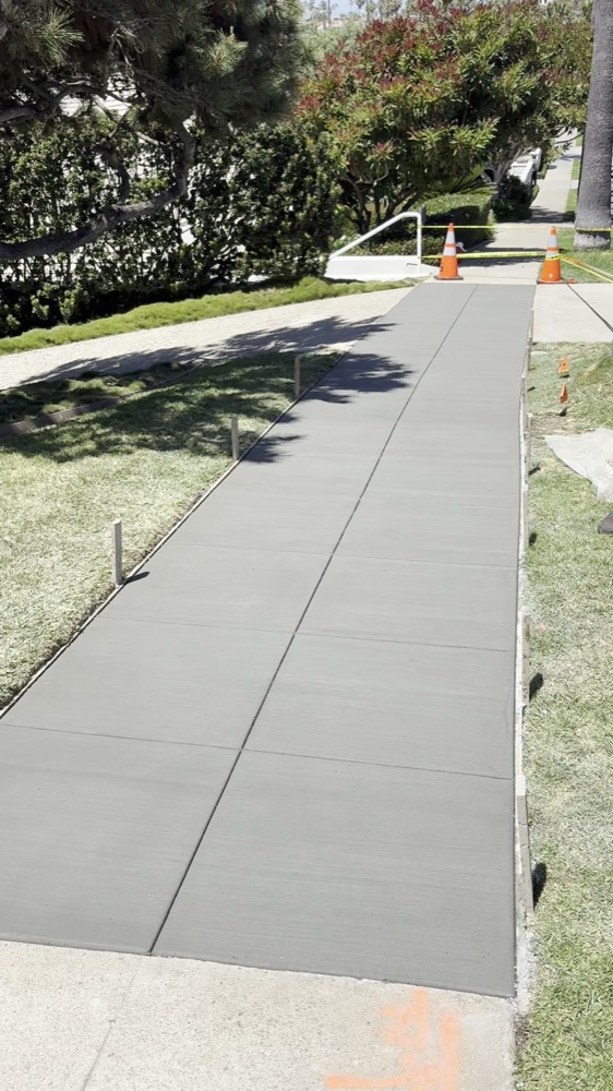 Finished replacement sidewalk — new concrete, crisp joints, edges backfilled